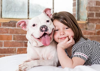 little girl laying on bed with her dog. dog photographer