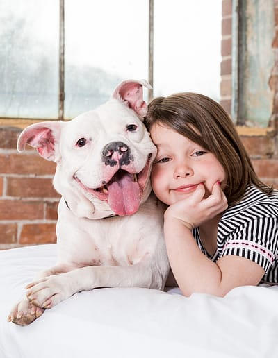 little girl laying on bed with her dog. dog photographer