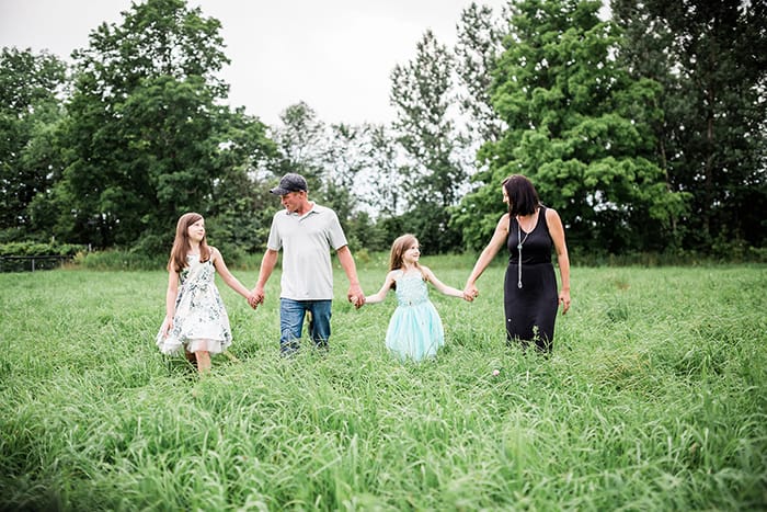 A family of four walking through a summer field